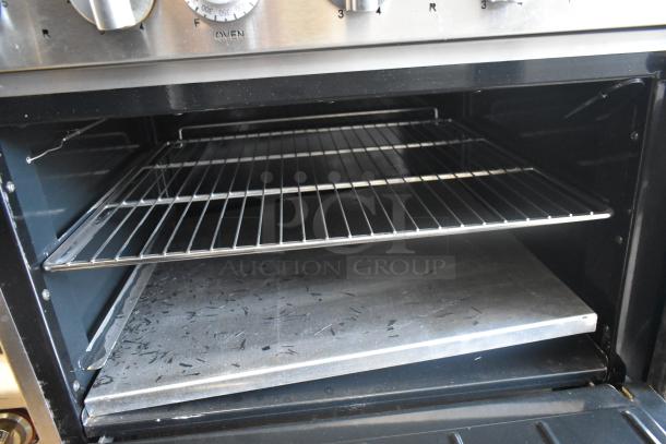 Imperial stainless steel commercial hot plate with 6 burners, side griddle, 2 ovens, overshelf, and backsplash.