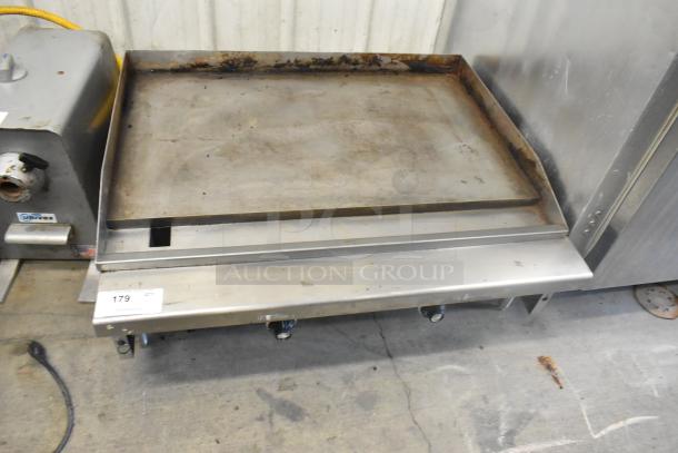 Stainless steel commercial countertop gas-powered griddle with a flat top, showing signs of use, label marked “179.”