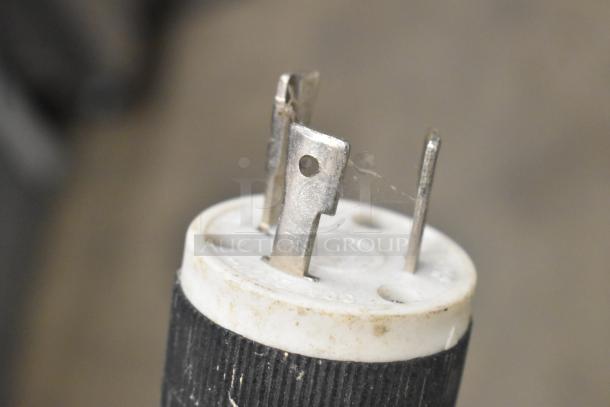 Close-up of a power plug from the Spaceman Forte 6265W ice cream machine, showing metal prongs and a used condition.