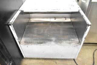 Stainless steel commercial horizontal open grab-n-go merchandiser, showing signs of wear, ideal for displaying ready-to-eat items.