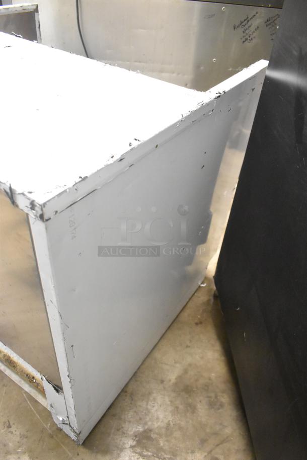 Stainless steel commercial horizontal open grab n go merchandiser, visible wear on edges, ideal for retail food display.