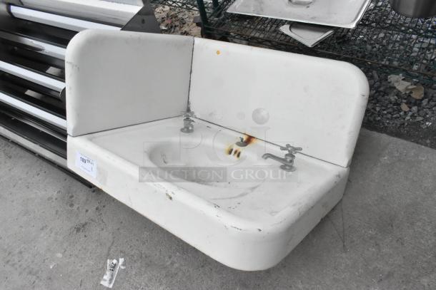Single bay wall mount sink with dual faucets, showing signs of rust and wear, for auction.