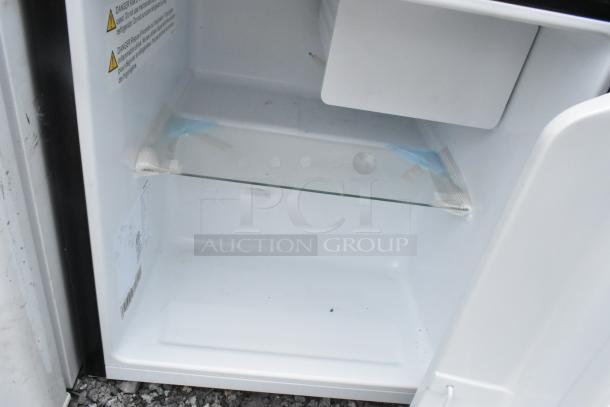 Hisense WMS017M6XBE mini cooler interior view showing glass shelf, visible caution labels, and clean condition.