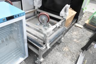 2 stainless steel equipment stands on commercial casters, excellent condition, with protective bubble wrap and visible markings.