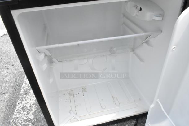 Interior of a mini cooler with a removable shelf and adjustable thermostat. Clean, white interior, visible light dust.