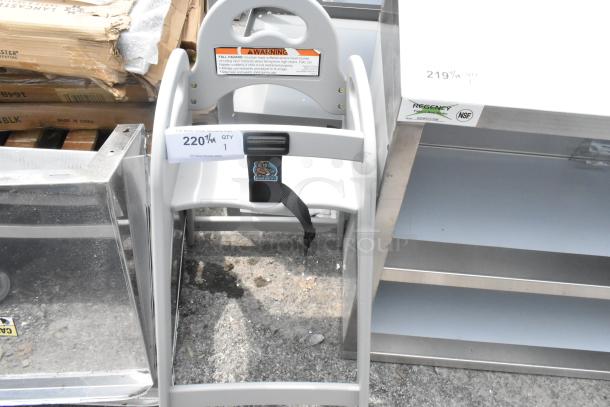 Brand new Koala Kare gray high chair, showing some scratches and dents. Includes safety strap and warning label.