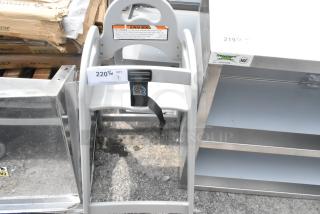 Brand new Koala Kare gray high chair, showing some scratches and dents. Includes safety strap and warning label.