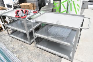 Two brand new gray metal 3-tier carts, scratch and dent condition. Includes red casters and plastic wrap protection.