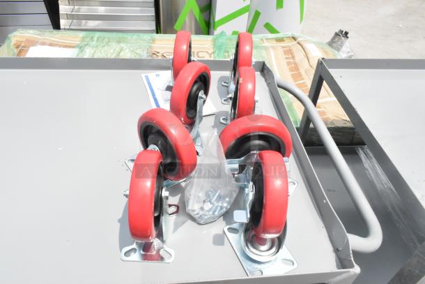 Gray metal three-tier carts with red wheels, brand new scratch and dent, includes hardware, 2 per bid.