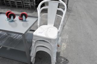 Stack of three brand new white metal Tolix-style chairs, minor scratches visible, labeled "230 x 5."