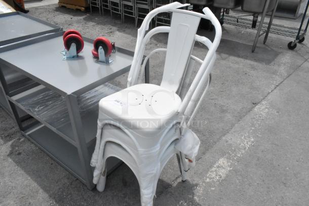 Stack of three brand new Tolix-style white metal chairs with minor dents, wrapped in protective material.