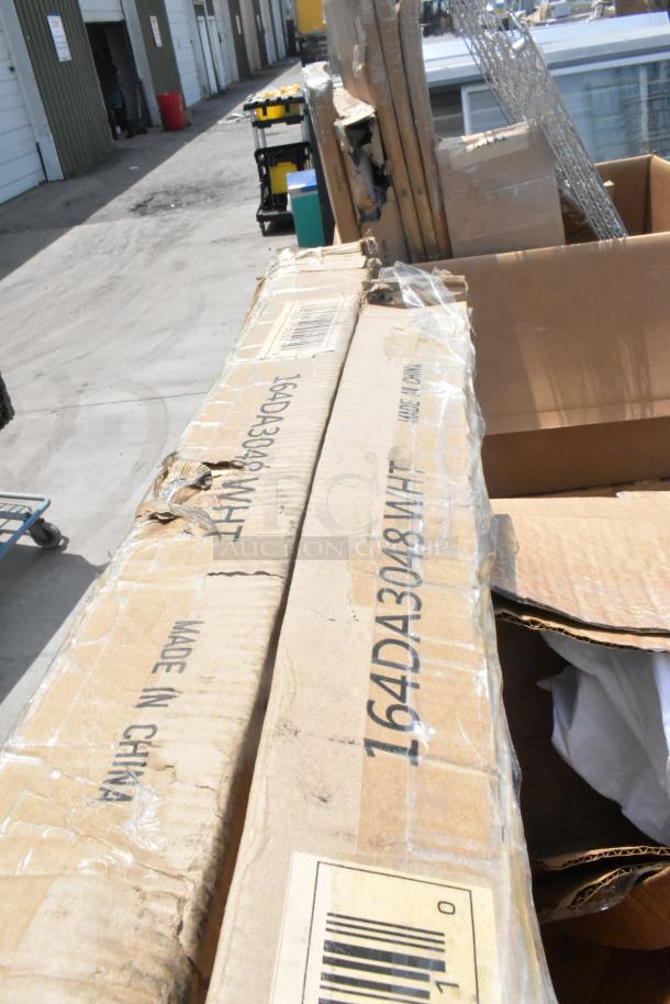 Damaged cardboard boxes labeled "Made in China" and "164DA3048WHT," containing new scratch-and-dent patio tables.