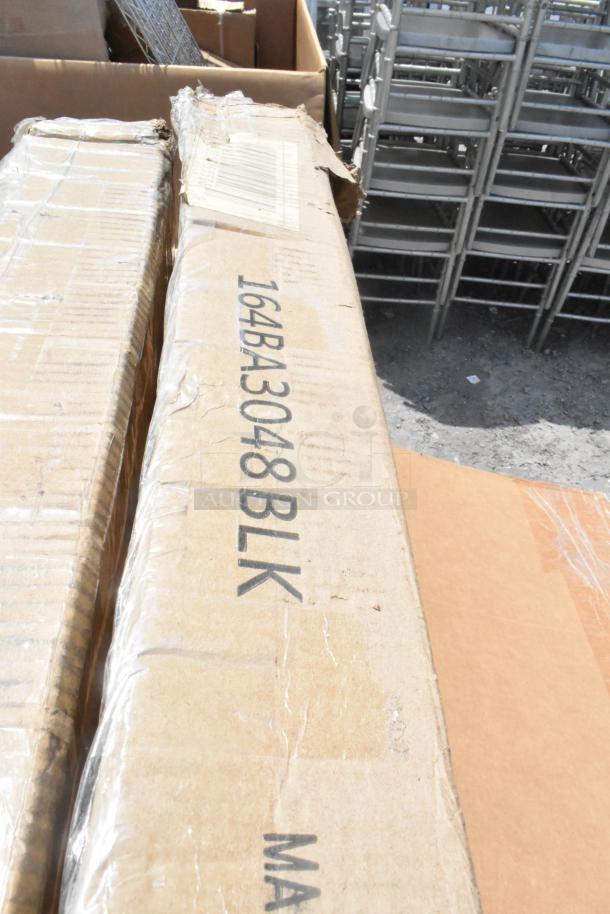 Cardboard box labeled "164BA3048BLK" containing new scratch and dent patio tables, part of a 7-item auction lot.
