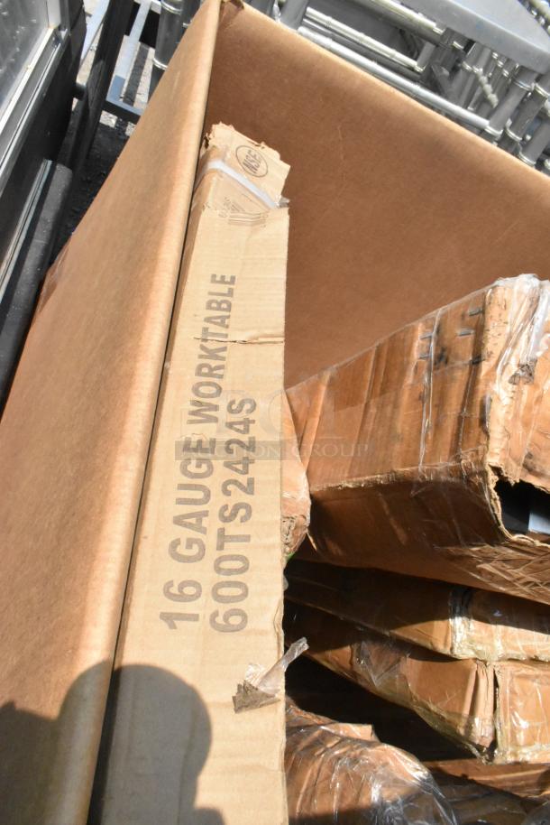 Cardboard box with "16 GAUGE WORKTABLE 600TS2424S" marking, containing scratch and dent items like tabletops and shelves.