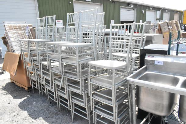 Stack of 50 light gray Chiavari banquet chairs, stackable, used condition. Ideal for events, weddings, or banquets.