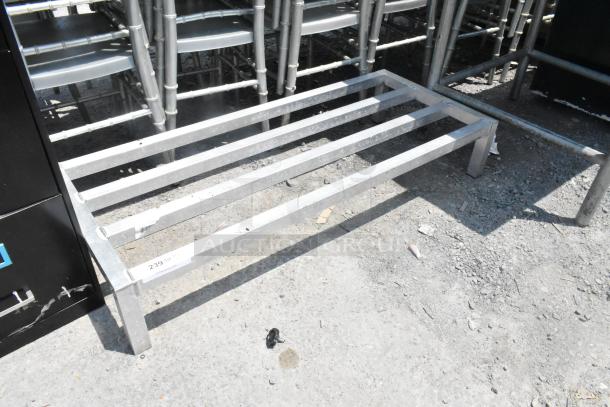 Metal Dunnage Rack with sturdy frame, five horizontal bars. Slight wear, label reads "239 lbs. capacity". Suitable for storage.
