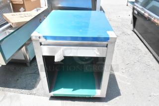 Stainless steel counter with drawer, under shelf, protective film, and slight wear. Ideal for kitchen or workshop use.