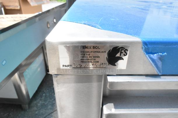 Stainless steel counter by Fenix Sol with drawer and under shelf. Includes label with company info and part number details.