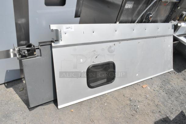 Two gray swinging kitchen doors with small windows, visible scuff marks, and a metal hinge mechanism. Label reads "246th QTY 2".