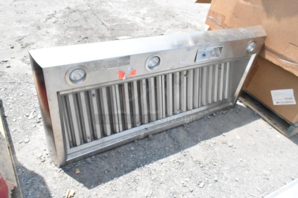 Stainless steel range hood with dual light fixtures and vent controls, used condition, visible surface scratches.