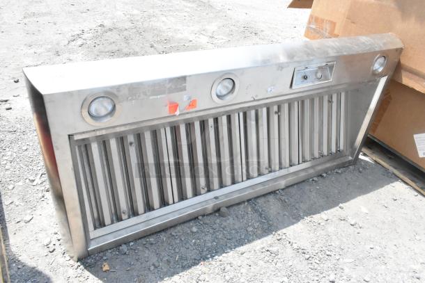 Stainless steel range hood with dual fan vents, built-in lights, and control panel. Light wear visible.