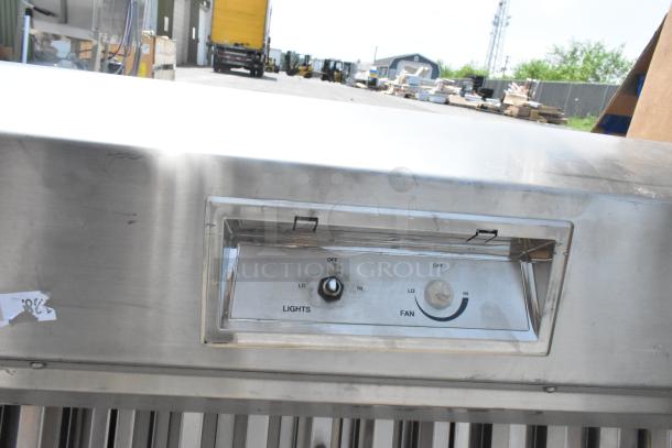 Stainless steel range hood with control panel for lights and fan speed settings. Slightly used condition with minor scratches.