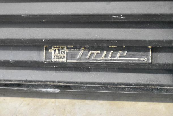 Close-up of True GDM-23F logo plate on metal commercial cooler, showing manufacturer branding and model details.
