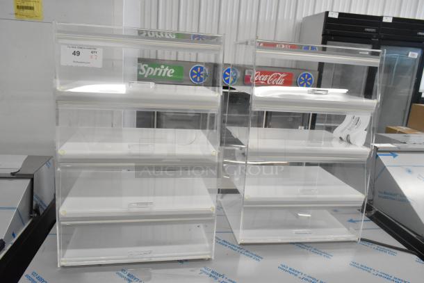 2 clear poly countertop dry display case merchandisers with three shelves each, ideal for showcasing products.