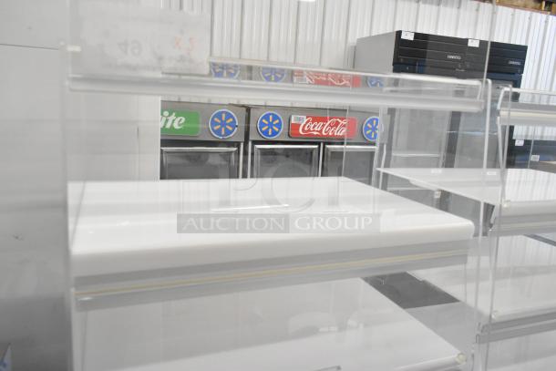 Two clear poly countertop dry display cases, excellent condition, multi-tier shelves for merchandising, suitable for retail use.