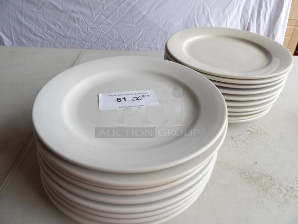 "12-inch round white stoneware plates, set of 20, stacked on a table. Condition: good. Auction label indicates quantity."