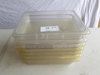 Stack of 1/2 size clear polycarbonate food pans, 2.5" deep, labeled "74 QTY". Used condition with visible wear.