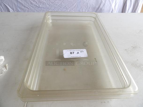 Full-size clear polycarbonate food pan, 2 1/2" deep, showing light wear. Auction tag reads "87, 2 QTY" from PCI Auctions.
