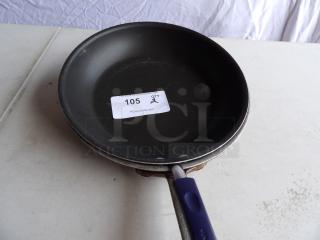 Rachael Ray 12" round aluminum skillet with black non-stick interior and blue handle, auction tag reads "105 QTY 2".