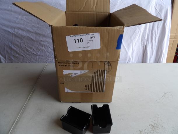 Cardboard box with open flaps, containing black plastic sugar packet holders. Box labeled "Made in China."