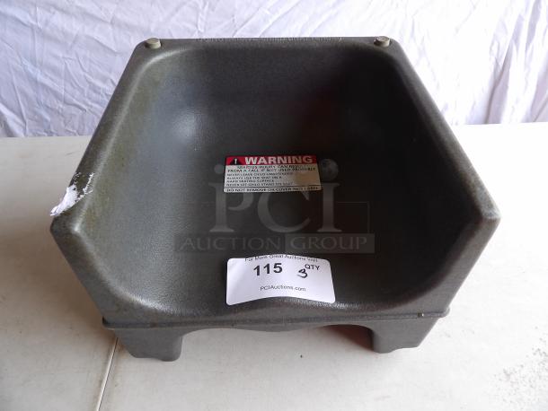 Brown hard plastic booster seat with warning label; auction tag labeled "115, Qty 3." Slight wear visible.