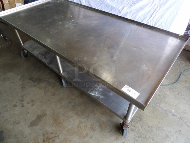 Stainless steel flat top table on casters, includes a lower shelf, suitable for commercial kitchens. Griddle not included.