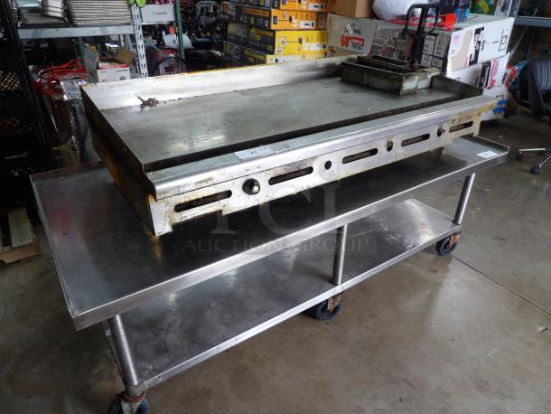 Flat top griddle table on casters, stainless steel, used condition, no griddle included, robust build, easy mobility.
