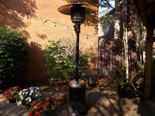 Metal propane gas powered outdoor patio heater in good condition, featuring a tall cylinder design and silver top.
