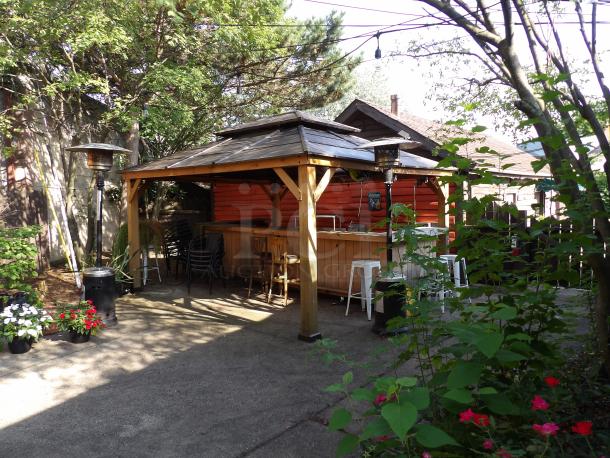 Outdoor cedar-framed gazebo, 16x12 ft, steel hardtop, wooden finish, like-new condition. Buyer must dismantle.