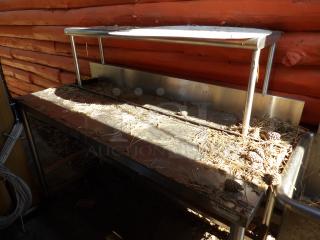 Win-Holt stainless steel table with upper shelf, used condition, featuring metal frame and visible dirt, potential for cleaning.
