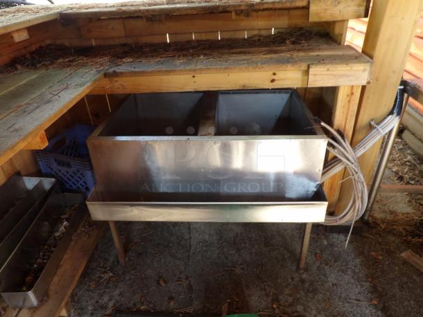 Industrial stainless steel ice well with bottle tray, dual compartments, sturdy construction, signs of outdoor wear.