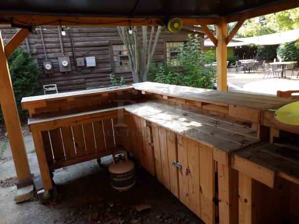 L-Shape wood bar on casters, 8' long, 48" wide, 44" tall. Features natural wood finish, storage cabinets, visible propane tank.