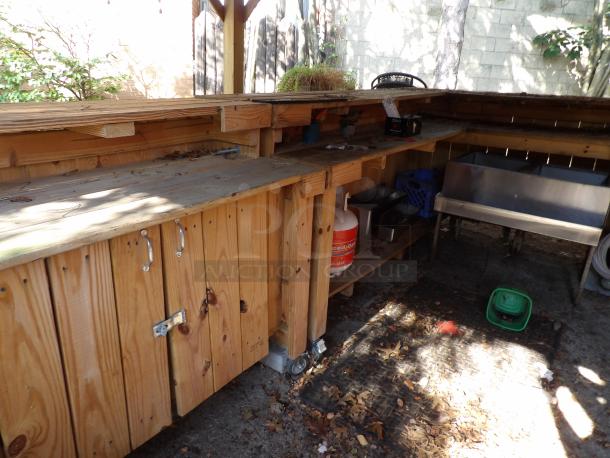 L-shape wood bar on casters, 8' long, 48" wide x 44" tall, features storage and metal sink, suitable for outdoor use.