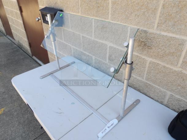 Adjustable glass food protector on metal stand, good condition, height adjustable, ideal for buffet or food display.