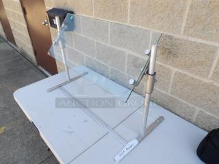 Adjustable glass food protector on metal stand, good condition, height adjustable, ideal for buffet or food display.
