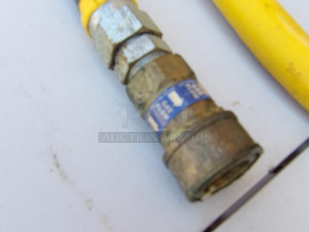 3/4" gas line with metal fittings and yellow coating, showing moderate wear. Small blue label indicates specs.