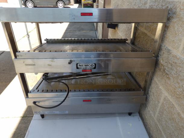 Nemco 6480-30S stainless steel 2-tier heated display case with rear access. Features caution labels, power cable, on legs.