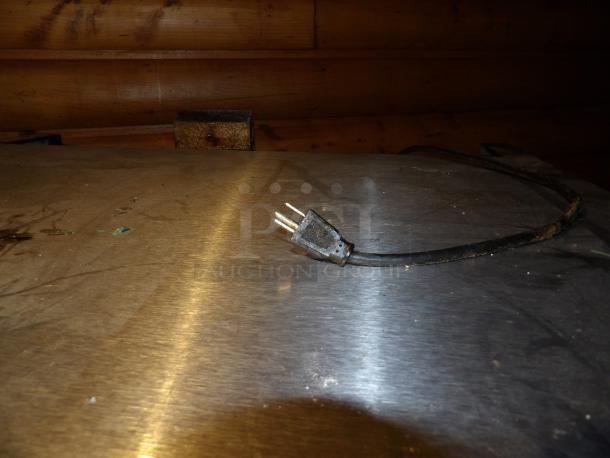 Plug and power cord on a stainless steel surface, showcasing the electrical connection component of the commercial oven.