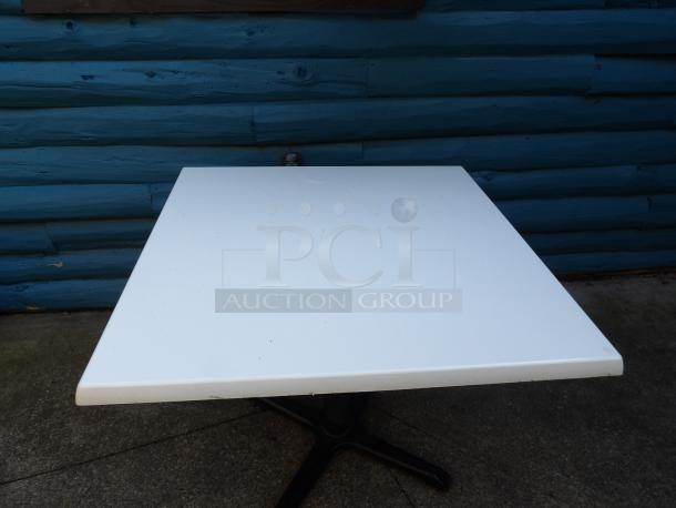 Heavy-duty outdoor dining table with composite top, approximately 36" square and 30" high, in excellent condition.