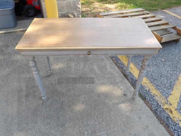 Wood desk with drawer, light finish, turned legs, minor surface wear, suitable for vintage or rustic decor.